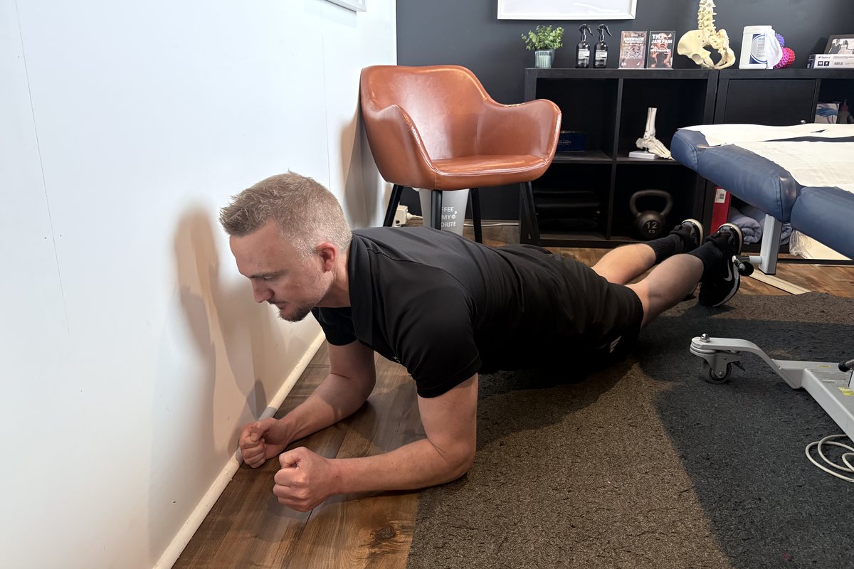 Dale Peirson holding a forearm plank on the floor of the Mornington Peninsula Myotherapy treatment room