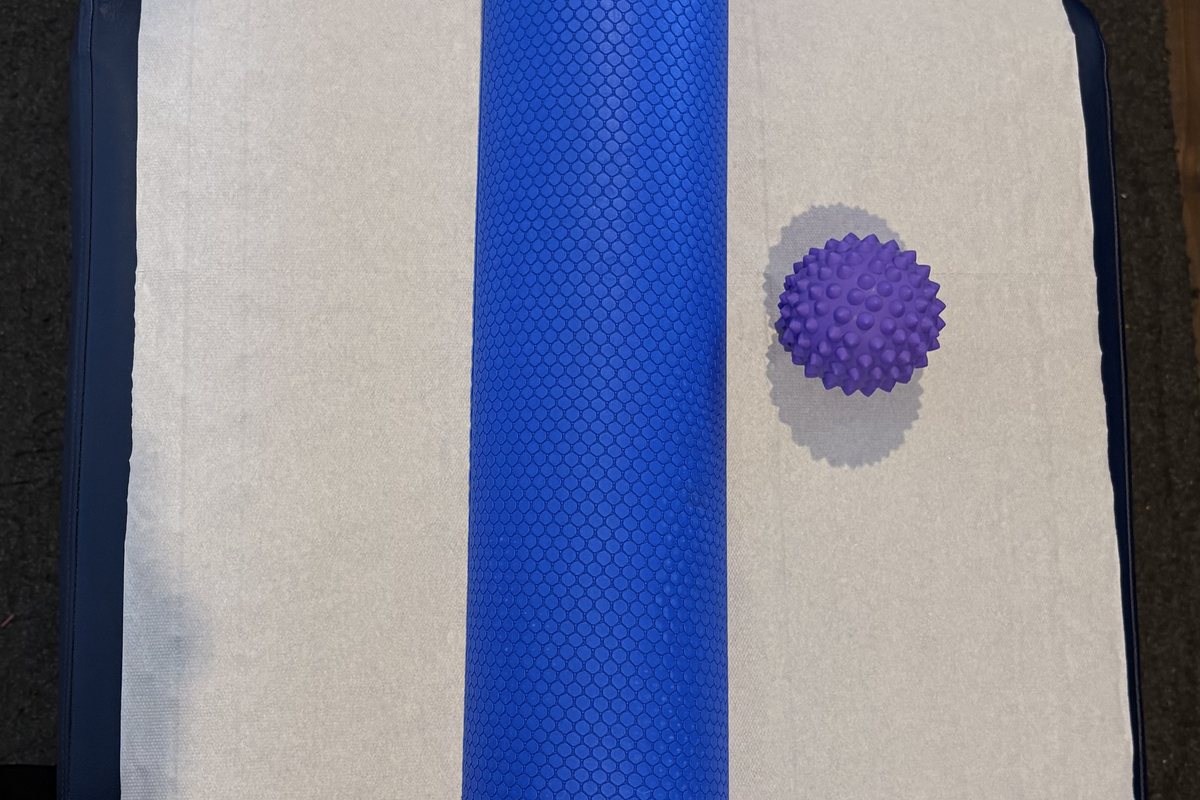 A blue foam roller and a spiky purple massage ball on the treatment table