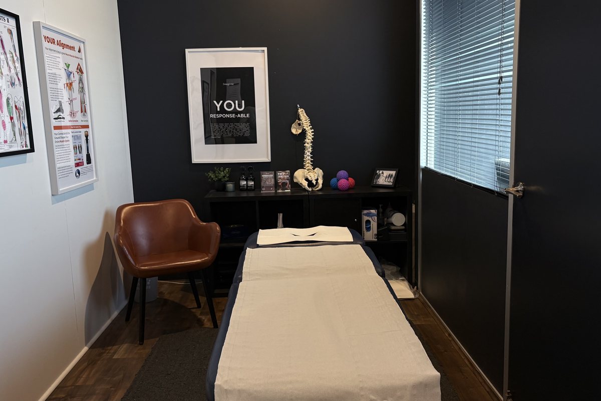 A treatment room at Mornington Peninsula Myotherapy, with the table made up, anatomy charts and a spine model