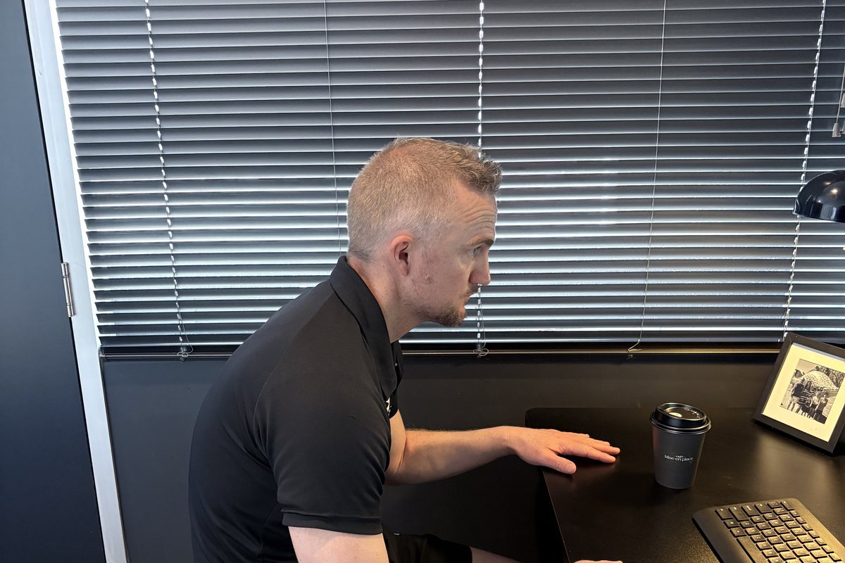 Dale Peirson sitting slumped at a desk with his head forward and shoulders rounded