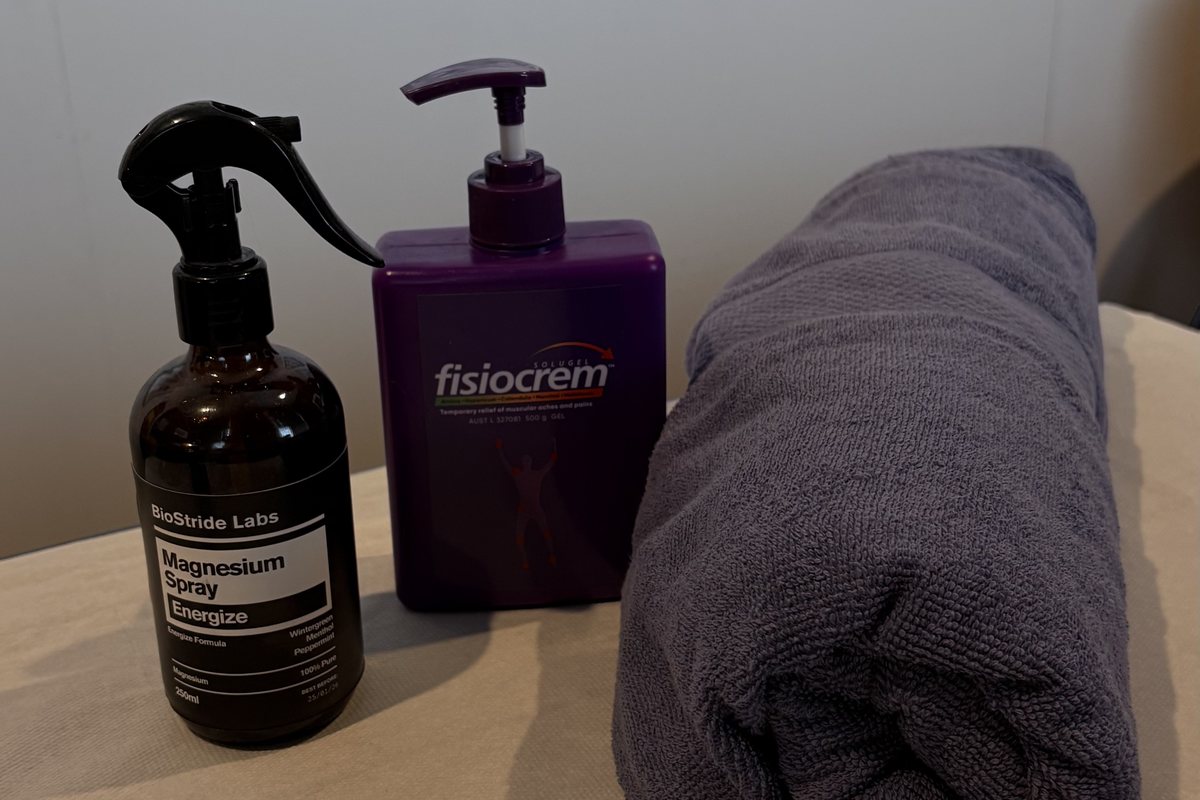 Magnesium spray, Fisiocrem and a rolled towel standing on the treatment table